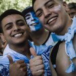 Excited fans in Buenos Aires showing enthusiasm with thumbs up and face paint.