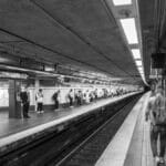 Black and white photo of a Boston subway station with people waiting on the platform.