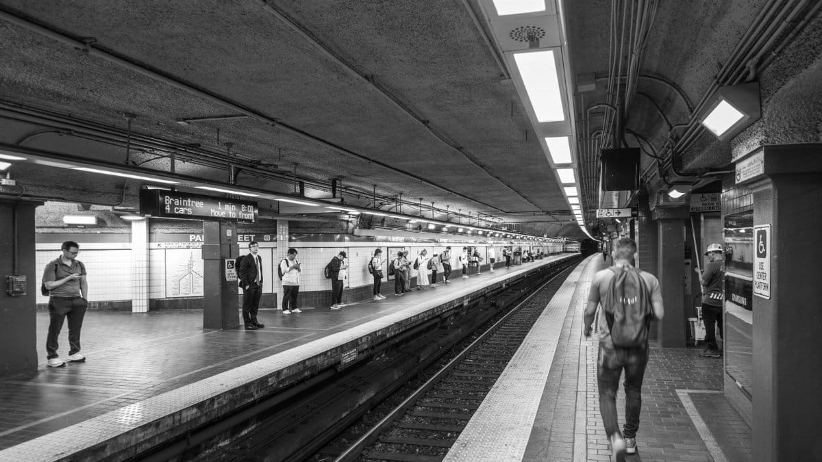 Black and white photo of a Boston subway station with people waiting on the platform.