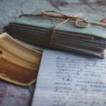 Stack of vintage letters tied with twine, a sepia photo, and a handwritten note on a wooden surface.