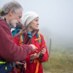 Two hikers consult a smartphone in a foggy rural landscape in Portugal.