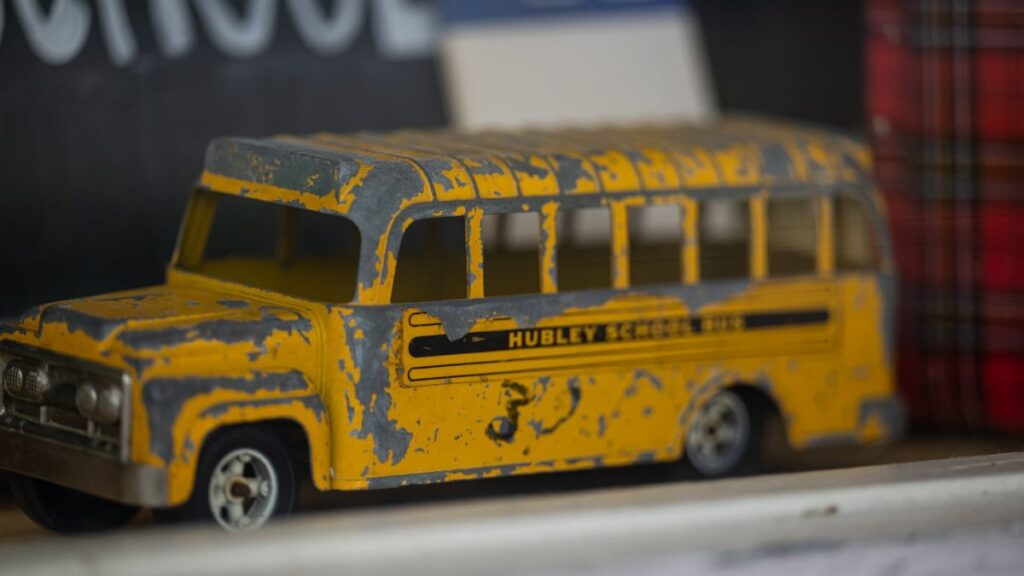 Close-up of a vintage toy school bus in yellow with a distressed finish.