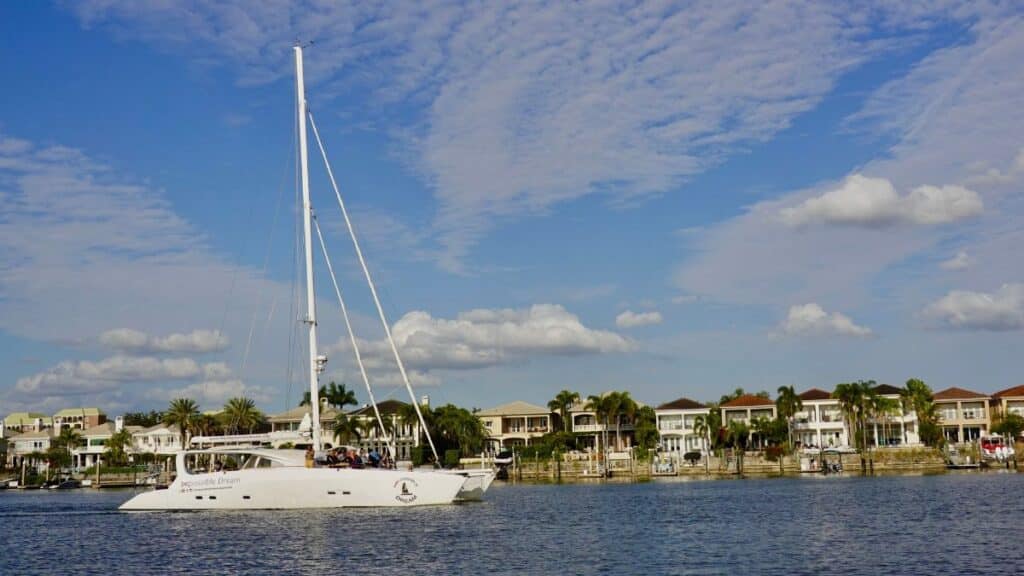 Yacht cruising in scenic Tampa Bay with waterfront homes and clear skies.