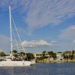 Yacht cruising in scenic Tampa Bay with waterfront homes and clear skies.