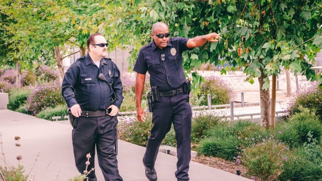 Two police officers walking along a park path in uniform, ensuring public safety.