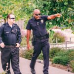 Two police officers walking along a park path in uniform, ensuring public safety.