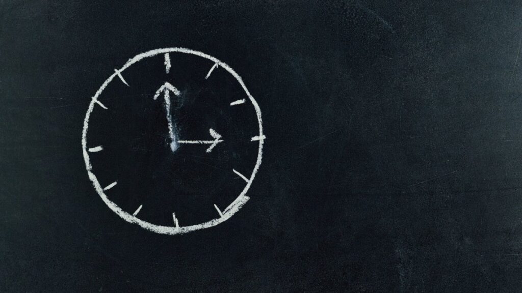 Chalk-drawn clock on a blackboard, symbolizing time and education concepts.