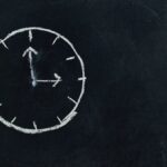Chalk-drawn clock on a blackboard, symbolizing time and education concepts.