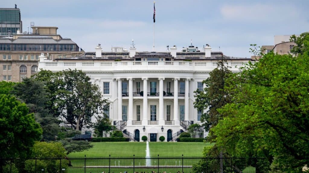 A scenic view of The White House, a renowned landmark in Washington, DC, surrounded by greenery and tourists.