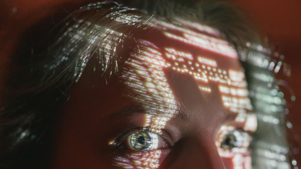 Close-up of a woman's eyes with digital patterns projected on her face, creating an abstract effect.