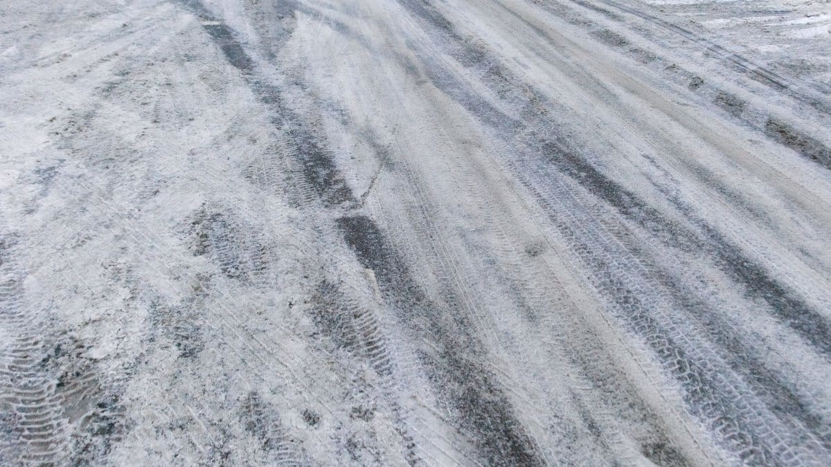 From above of rural road covered with snow and frost in cold winter day
