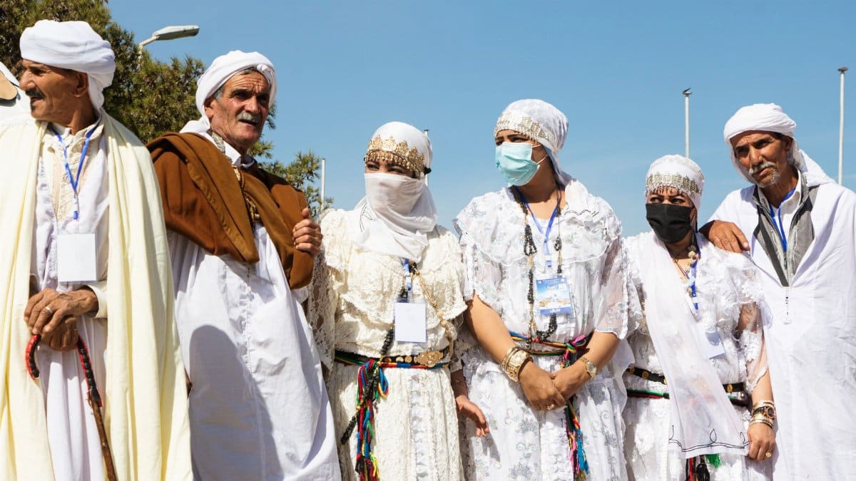 A group of people in traditional attire participating in a cultural festival outdoors under clear skies.