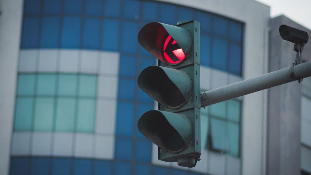 A red traffic light in front of a modern glass building in an urban environment, conveying safety and city life.