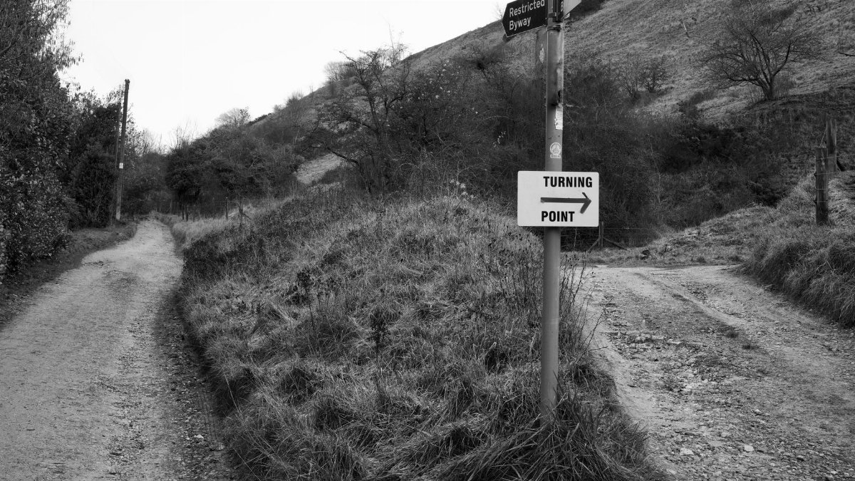 Black and white photo of a turning point in the Cheltenham countryside with directional signs.
