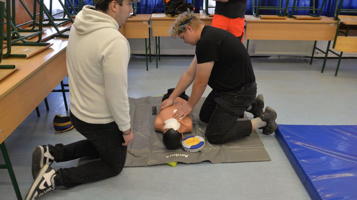 CPR training session with a dummy in a classroom environment.