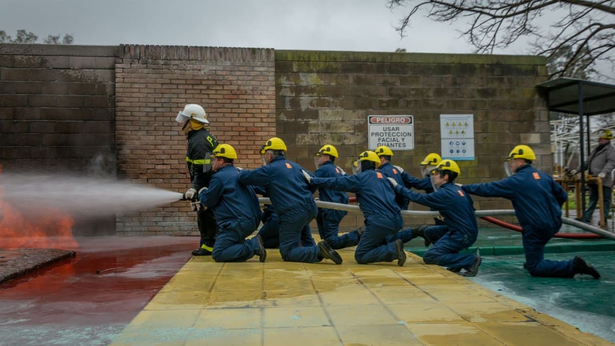 Firefighters practicing hose handling during outdoor training session, teamwork and safety focus.