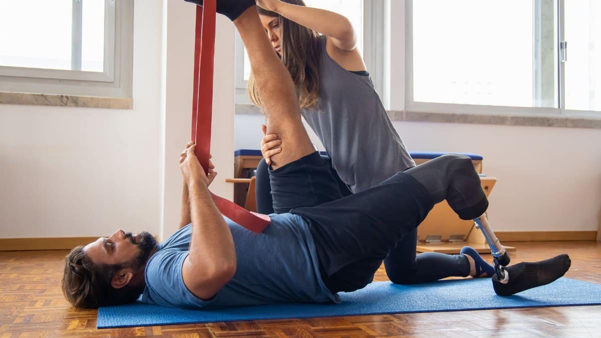 Man in rehabilitation exercises with a trainer, focusing on prosthetic leg recovery.