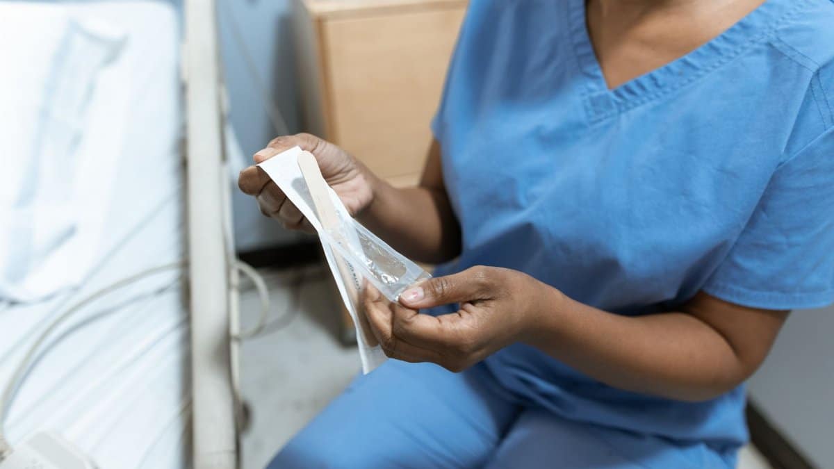 Close-up of a nurse unwrapping medical tools in a hospital setting, emphasizing care.