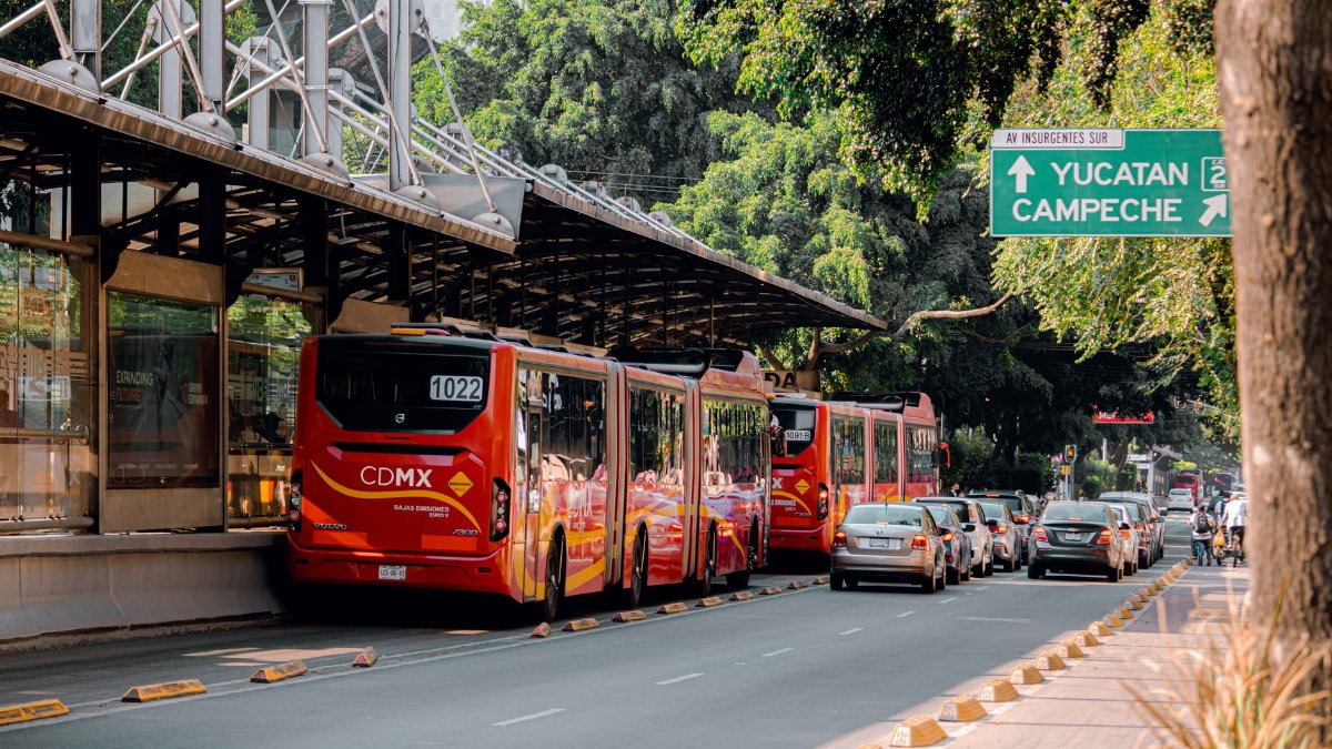 Red buses in a Mexico City transit station with vehicles on the road