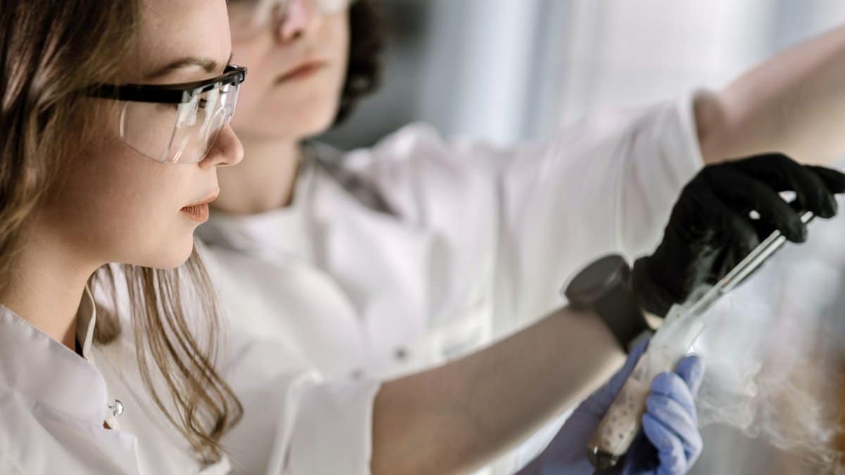 Two scientists in protective gear conducting a chemical experiment in a laboratory.