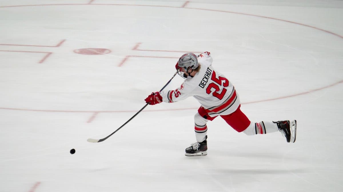 A professional ice hockey player takes a powerful shot on a rink.