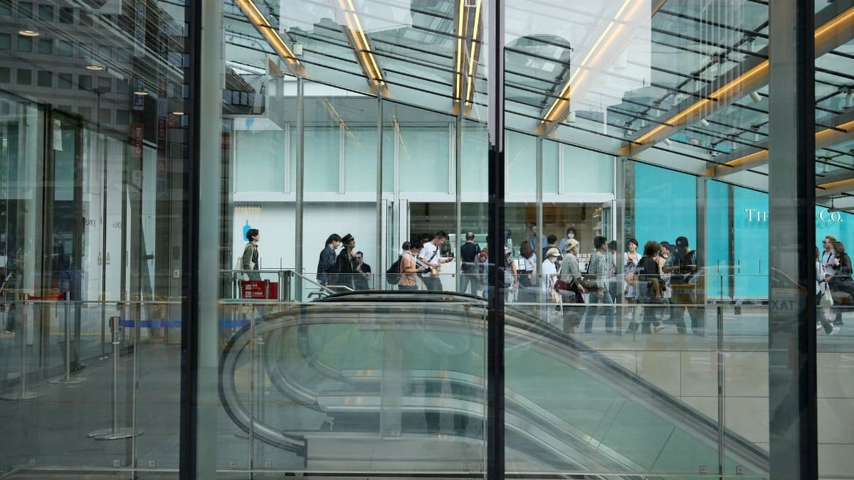 A bustling scene at Yokohama station with a crowd navigating modern escalators indoors.
