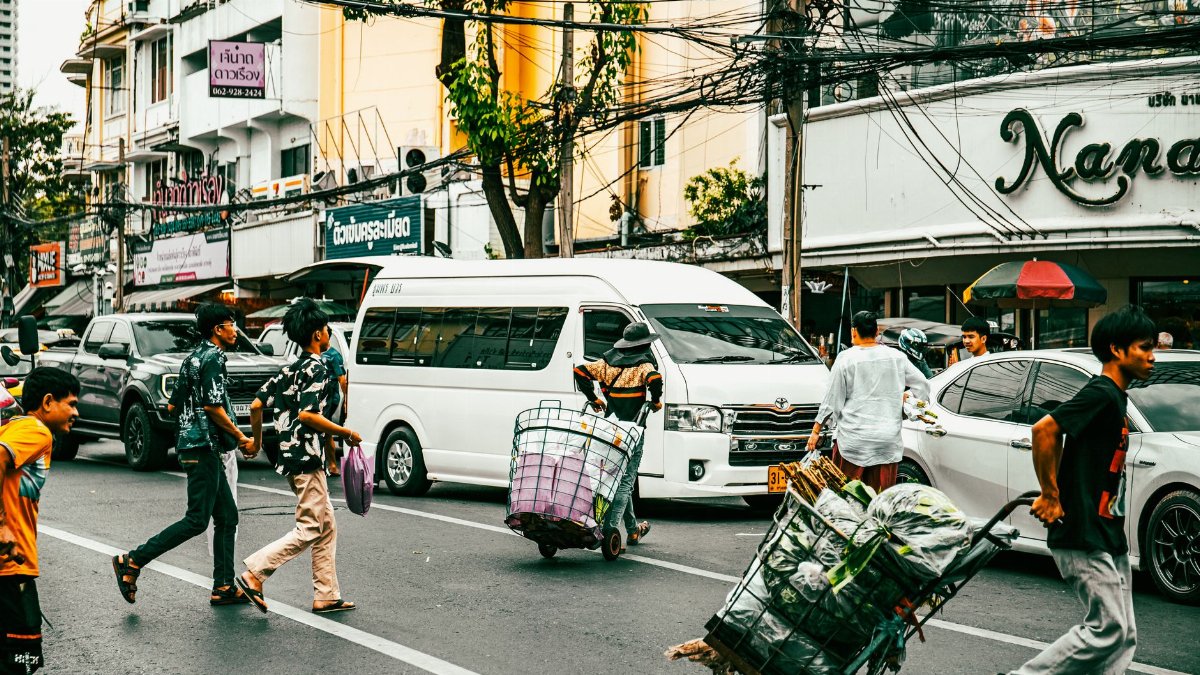 People crossing a bustling street in Bangkok, showcasing daily urban life and local culture.