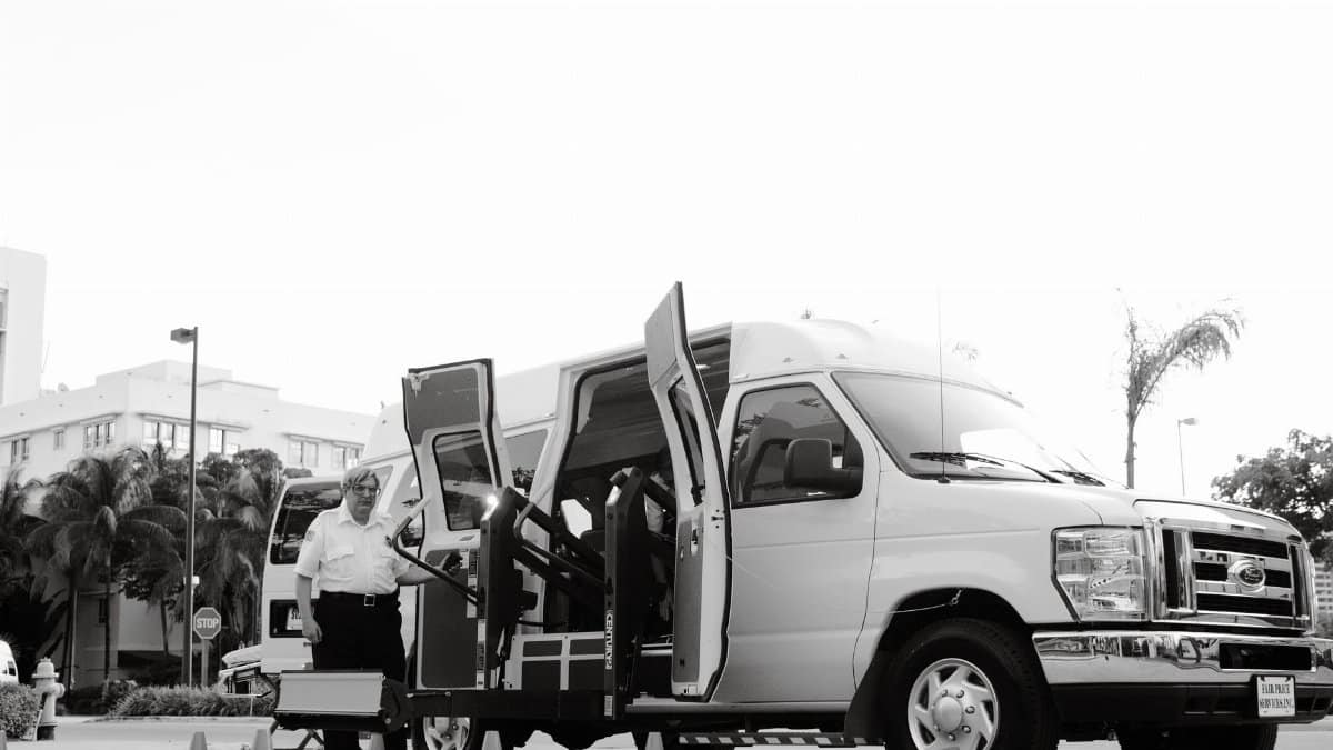 A black and white image depicting an accessible transport van with a lift, enhancing mobility for passengers with disabilities.
