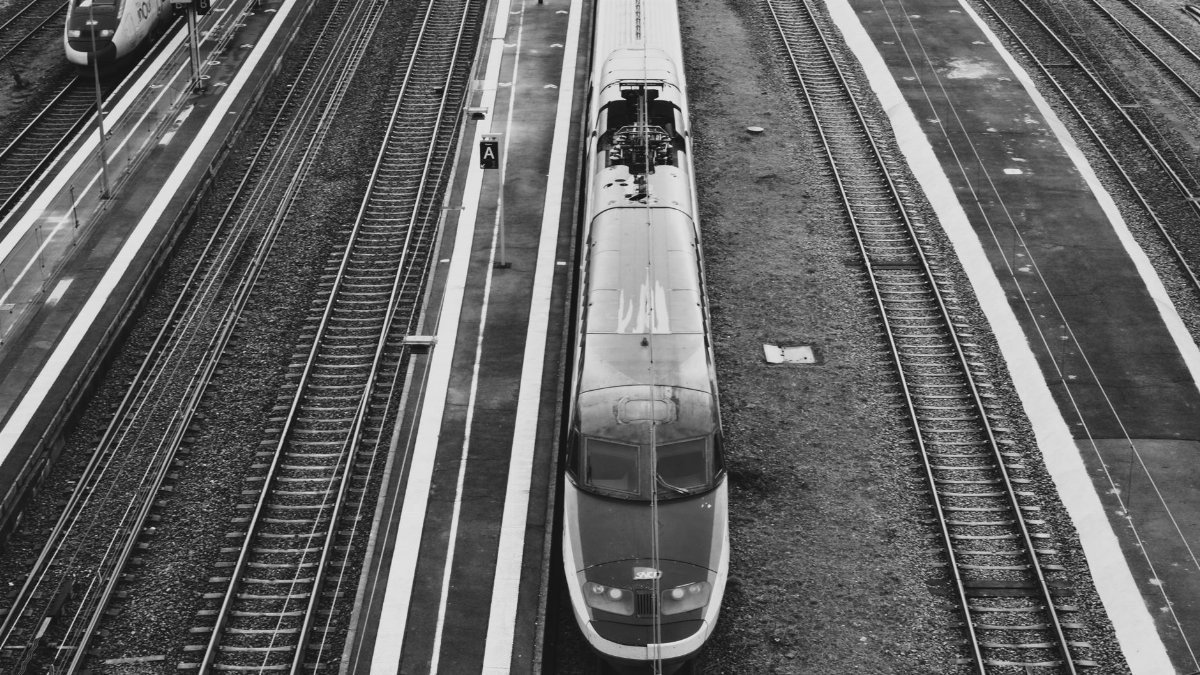 Black and white aerial view of a train at a railway station, showcasing urban transportation.