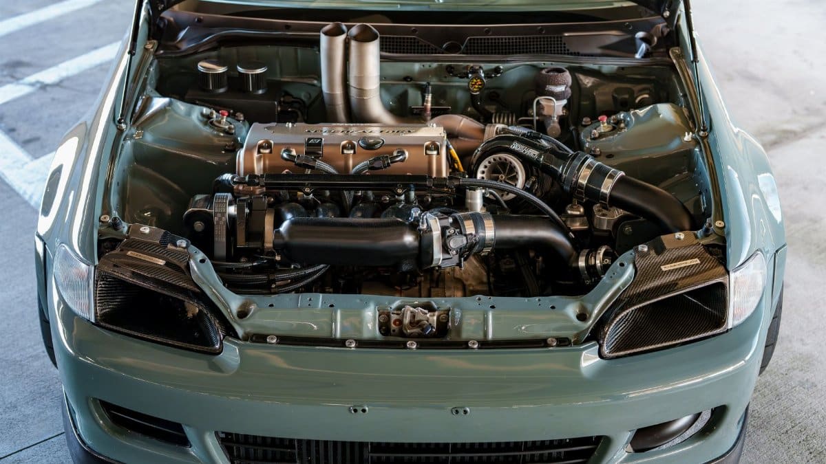 Close-up view of a modified car engine in an open hood sports car, showcasing mechanical details.