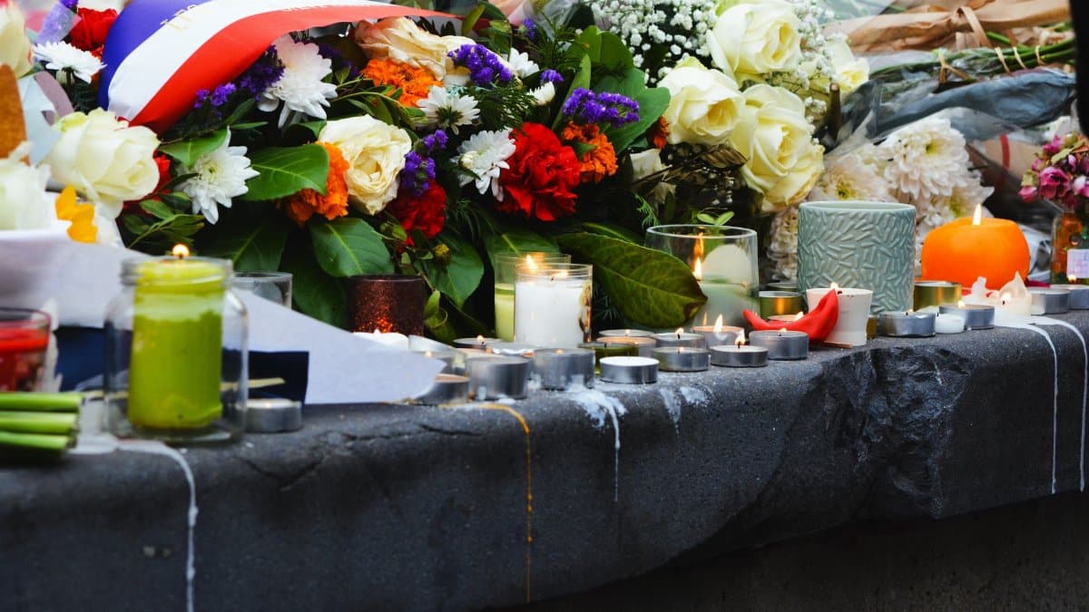 A serene memorial setup with candles and floral tributes on a stone surface outdoors.