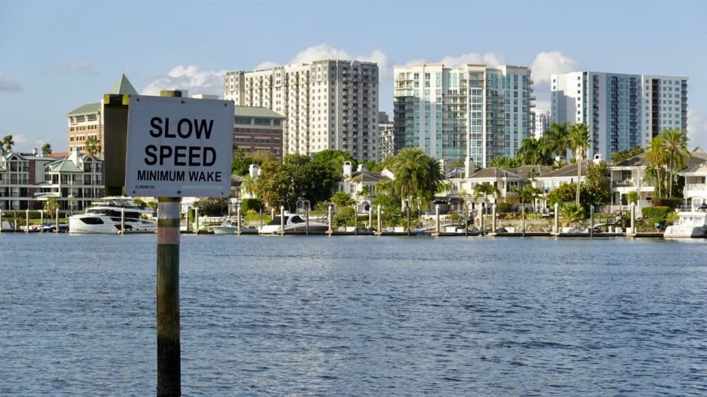 A picturesque view of downtown Tampa's waterfront with a 'Slow Speed' sign and modern buildings in the background.