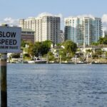 A picturesque view of downtown Tampa's waterfront with a 'Slow Speed' sign and modern buildings in the background.