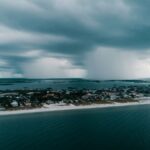 A stunning aerial view capturing a storm approaching an island village along the coast.