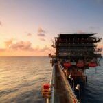A breathtaking view of an oil platform on the ocean at sunset, showcasing industrial beauty.
