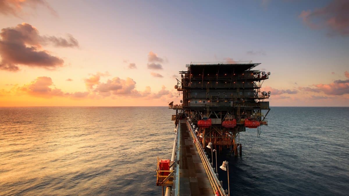 A breathtaking view of an oil platform on the ocean at sunset, showcasing industrial beauty.