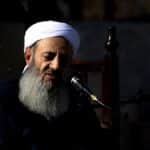 A religious leader speaks passionately during an outdoor Islamic ceremony.
