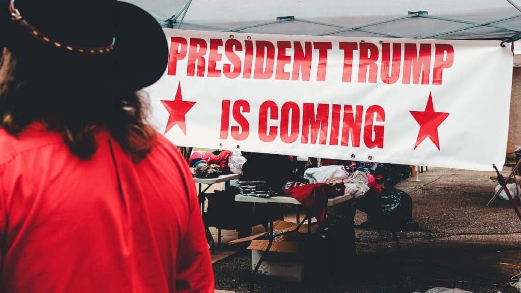 Banner promoting a political event for Donald Trump in Wheeling, WV with market stalls.
