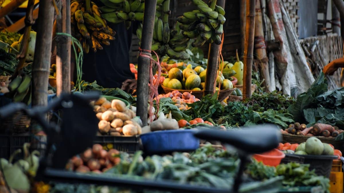 Colorful display of fresh fruits and vegetables at a bustling market stall in Odisha, India.
