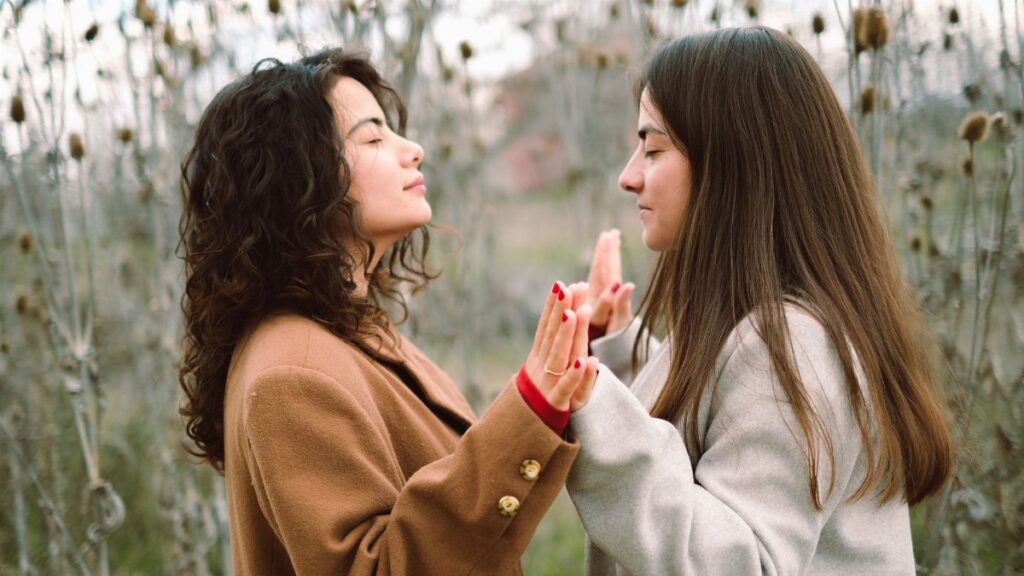Two young women engage in a mindful meditation practice in a serene natural setting, fostering relaxation and connection.