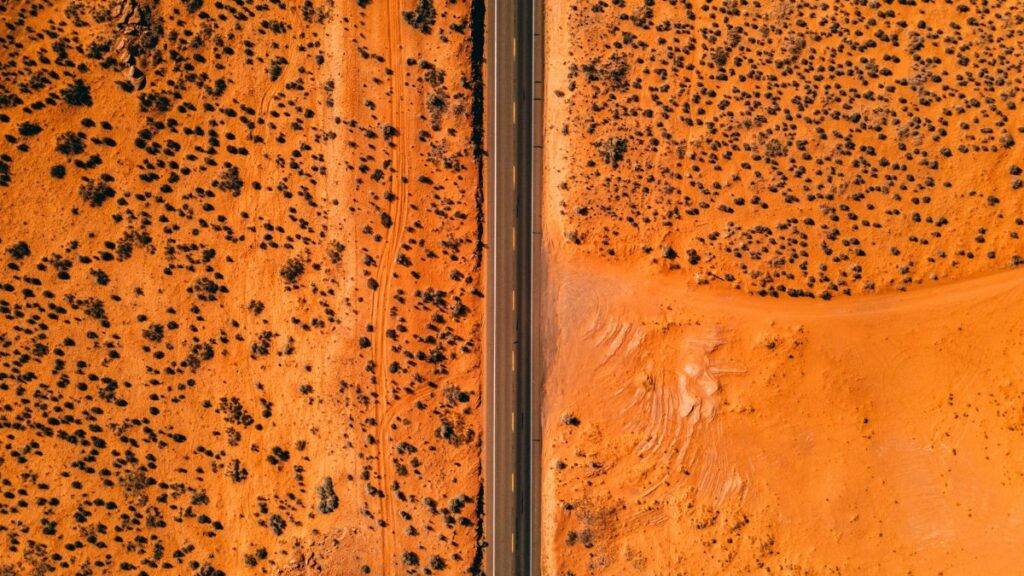 Stunning aerial view of a straight highway cutting through the barren Arizona desert landscape.