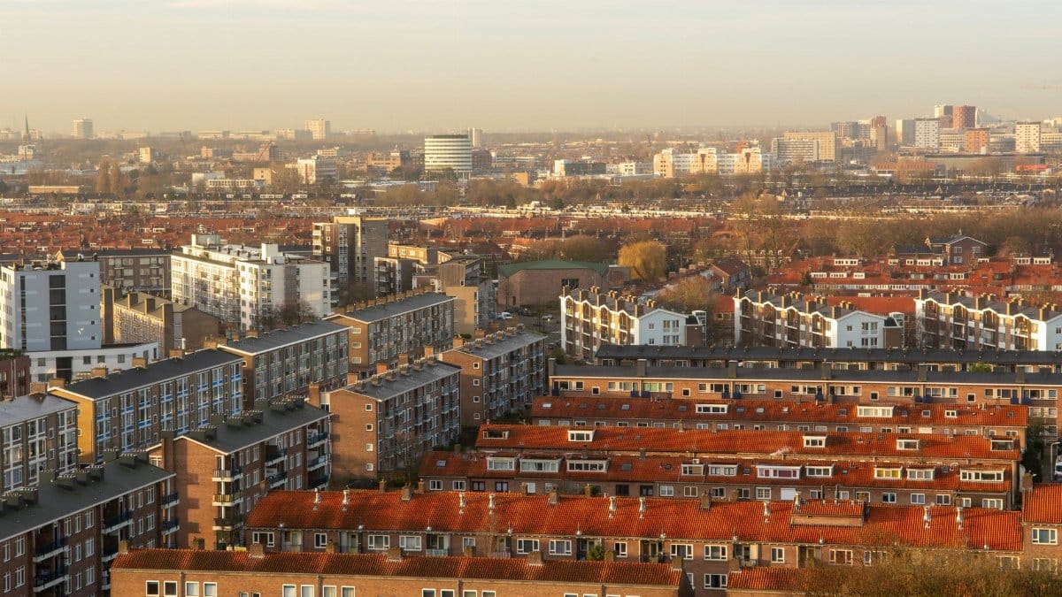 Aerial view of a cityscape featuring dense residential housing under a warm sunset glow.