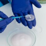 Researcher with gloves handling petri dish using laboratory equipment.