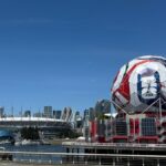 View of Vancouver's Science World featuring FIFA display and BC Place Stadium under a clear blue sky.