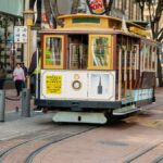 San Francisco cable car traveling through bustling downtown area, showcasing city life.