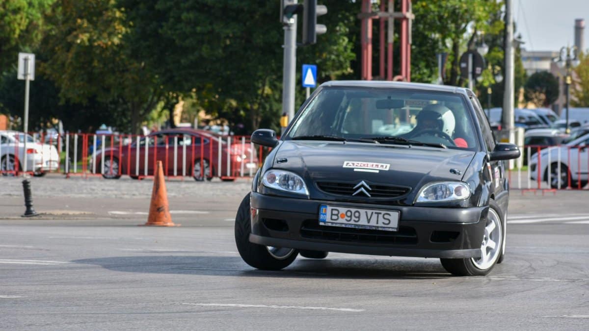 Black Citroen car takes a sharp turn during a street race in an urban setting.