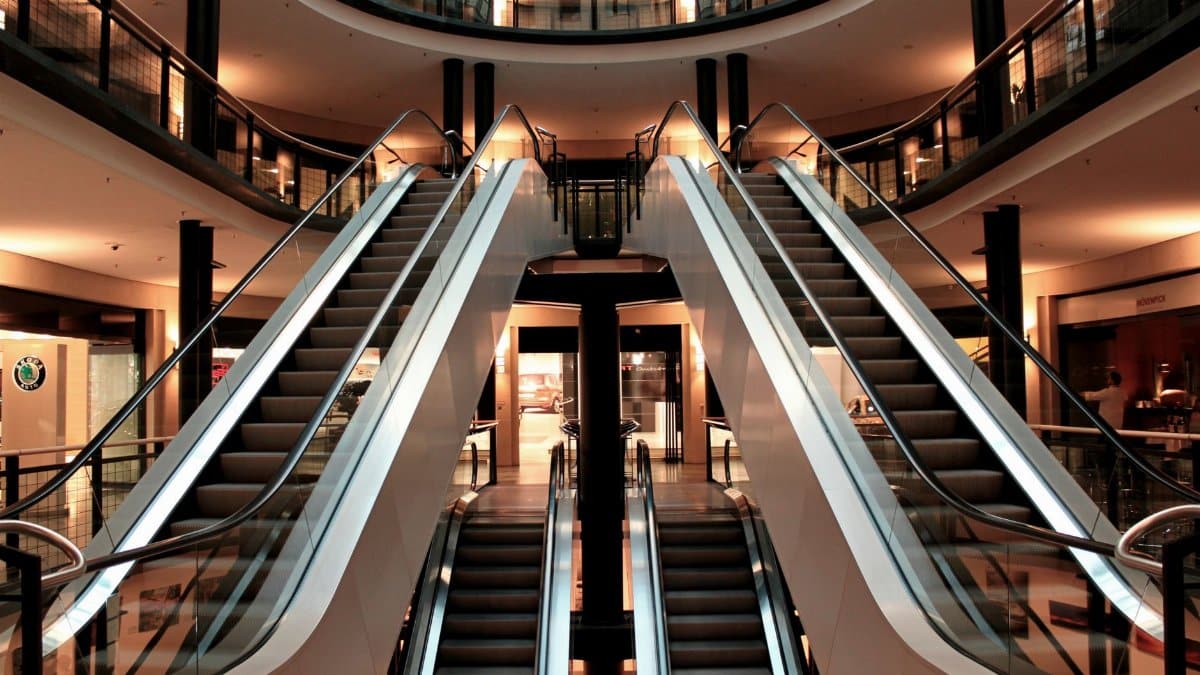 Symmetrical view of escalators in a modern shopping mall interior, showcasing architecture and design.