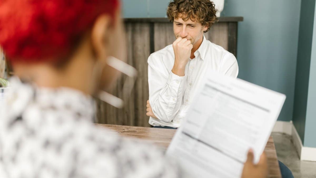 Man reflecting during a job interview in an office setting, highlighting thoughtfulness.