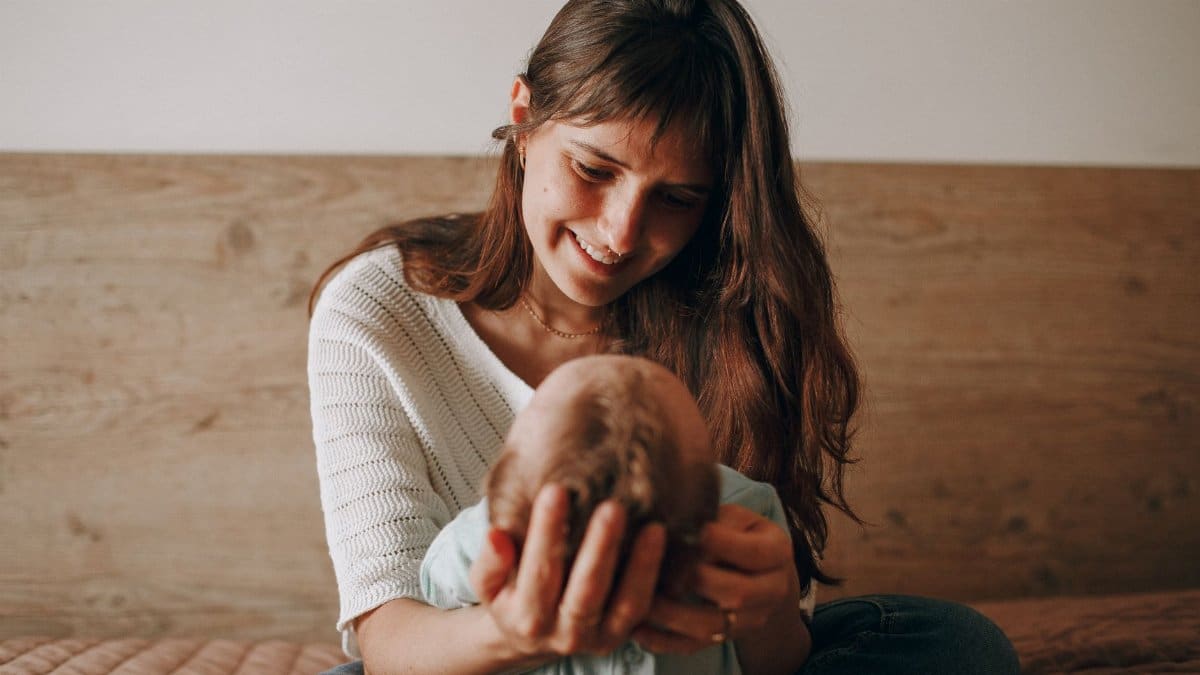 A loving mother gazes adoringly at her baby while holding them indoors.