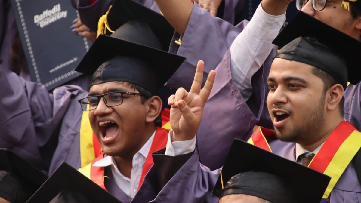 Group of excited graduates celebrating at university convocation with diplomas.